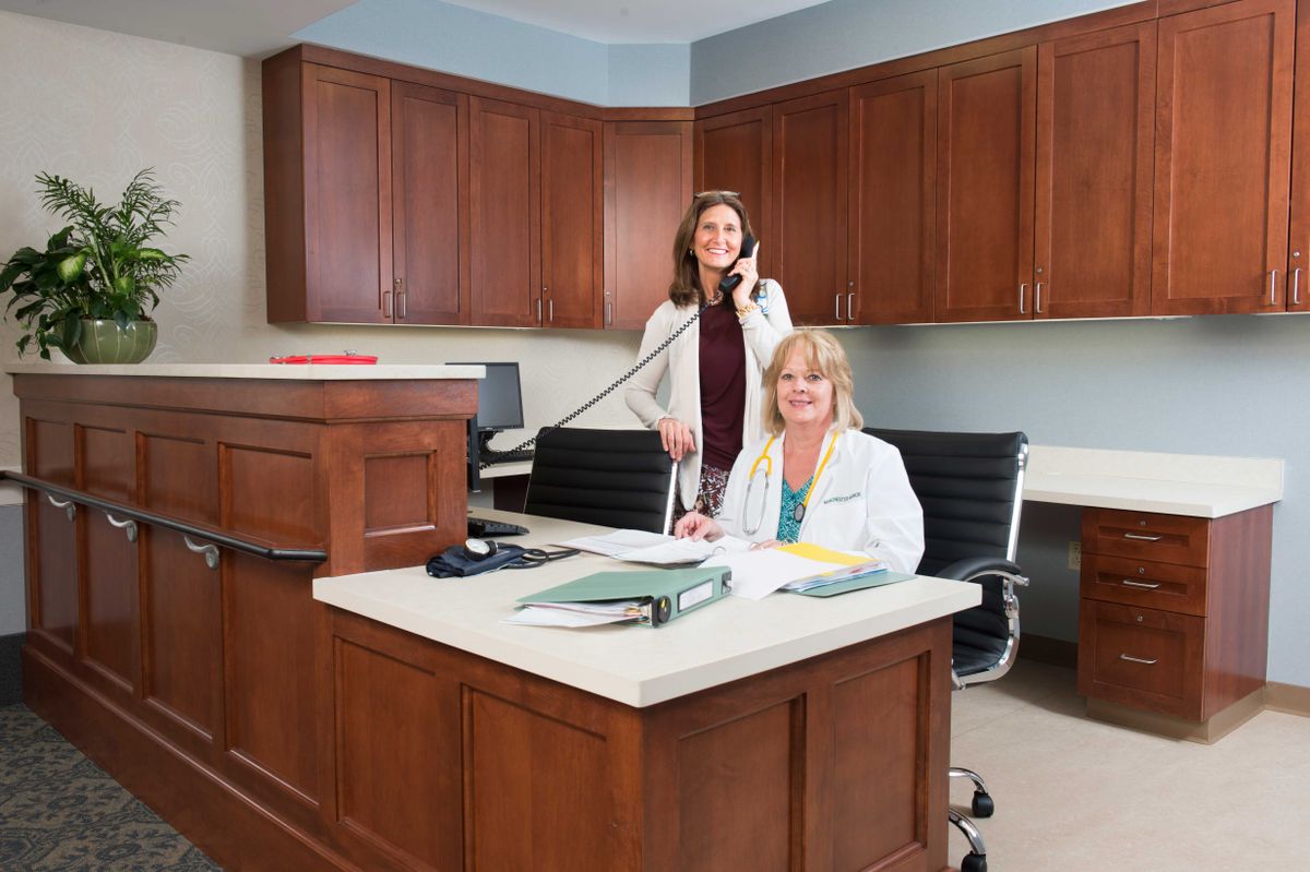 Two women working at a reception desk in a medical office.