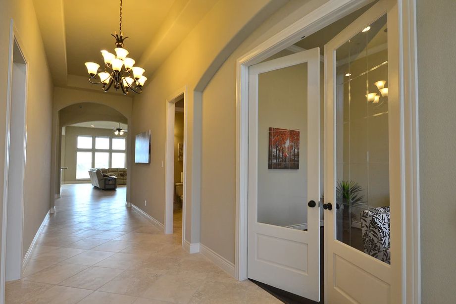 Spacious hallway with elegant lighting and a view into a bright room.