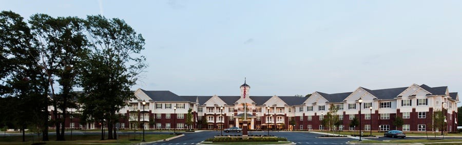 A large symmetrical building with a main entrance and an adjacent parking lot.