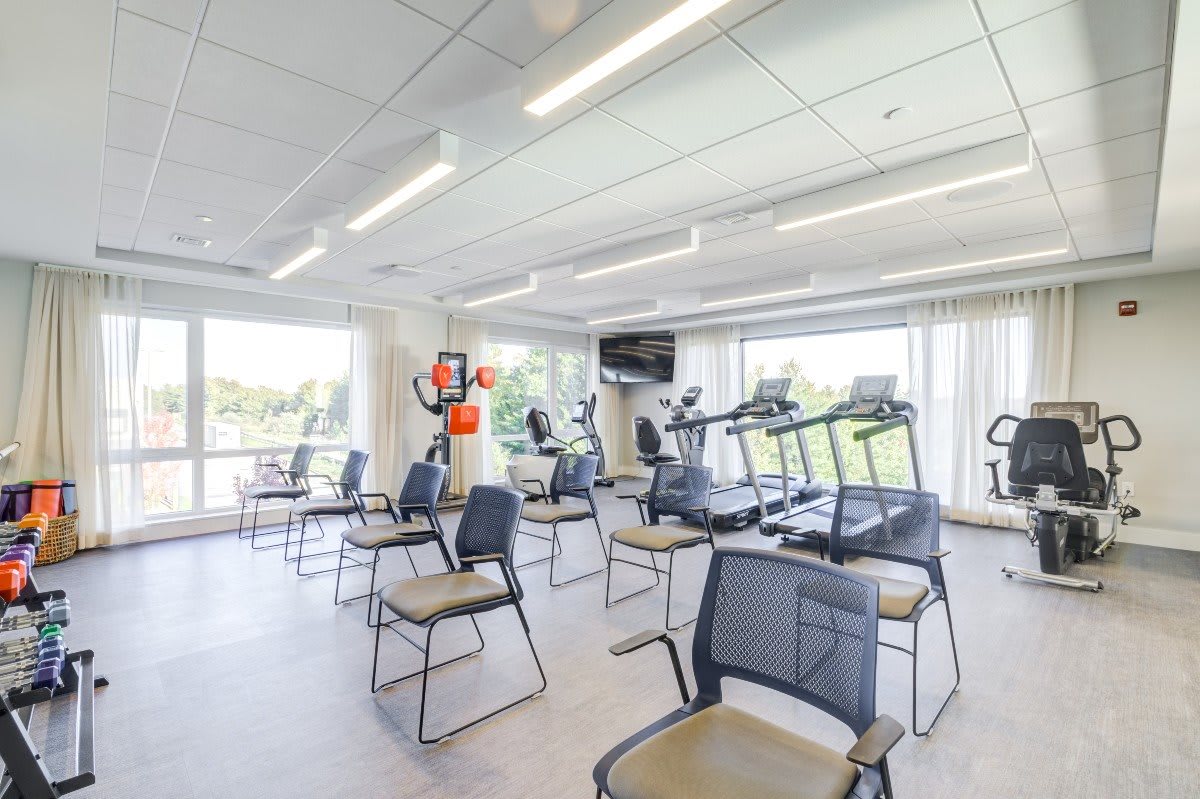 A bright and spacious gym with treadmills and chairs arranged for workout sessions.