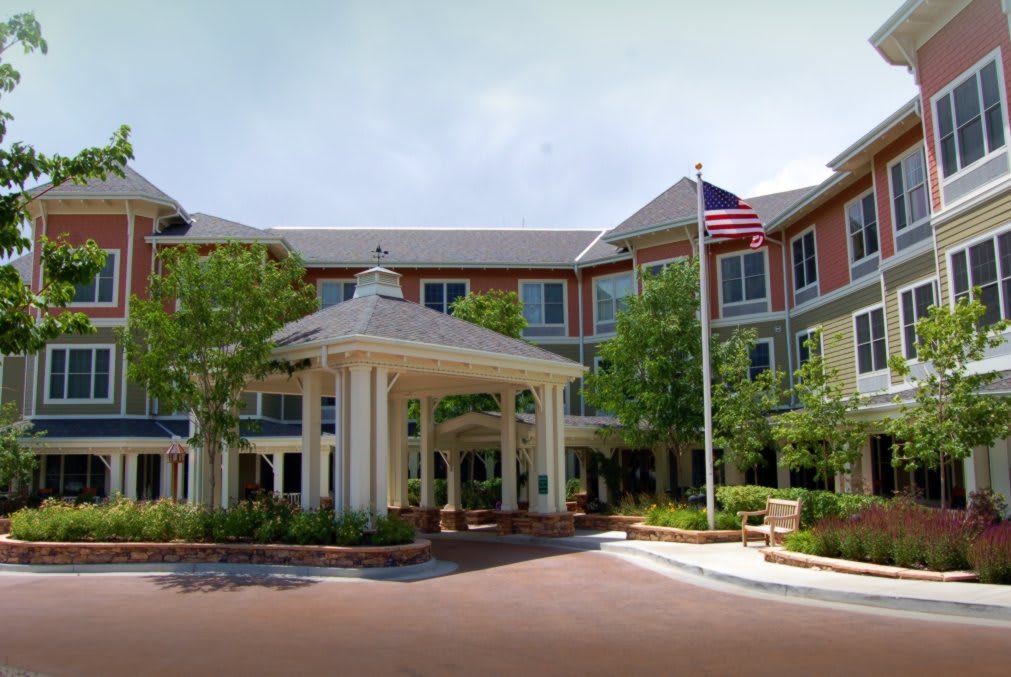 A well-maintained building entrance with a flagpole and surrounding greenery.