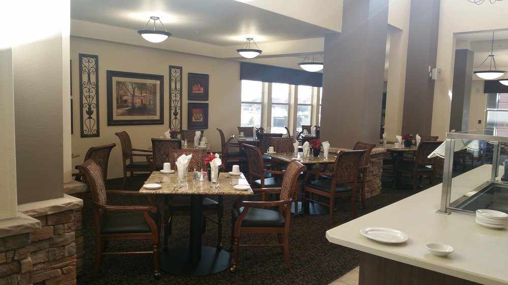 A cozy dining area with neatly arranged tables and chairs, adorned with simple decor and natural light streaming in through the windows.