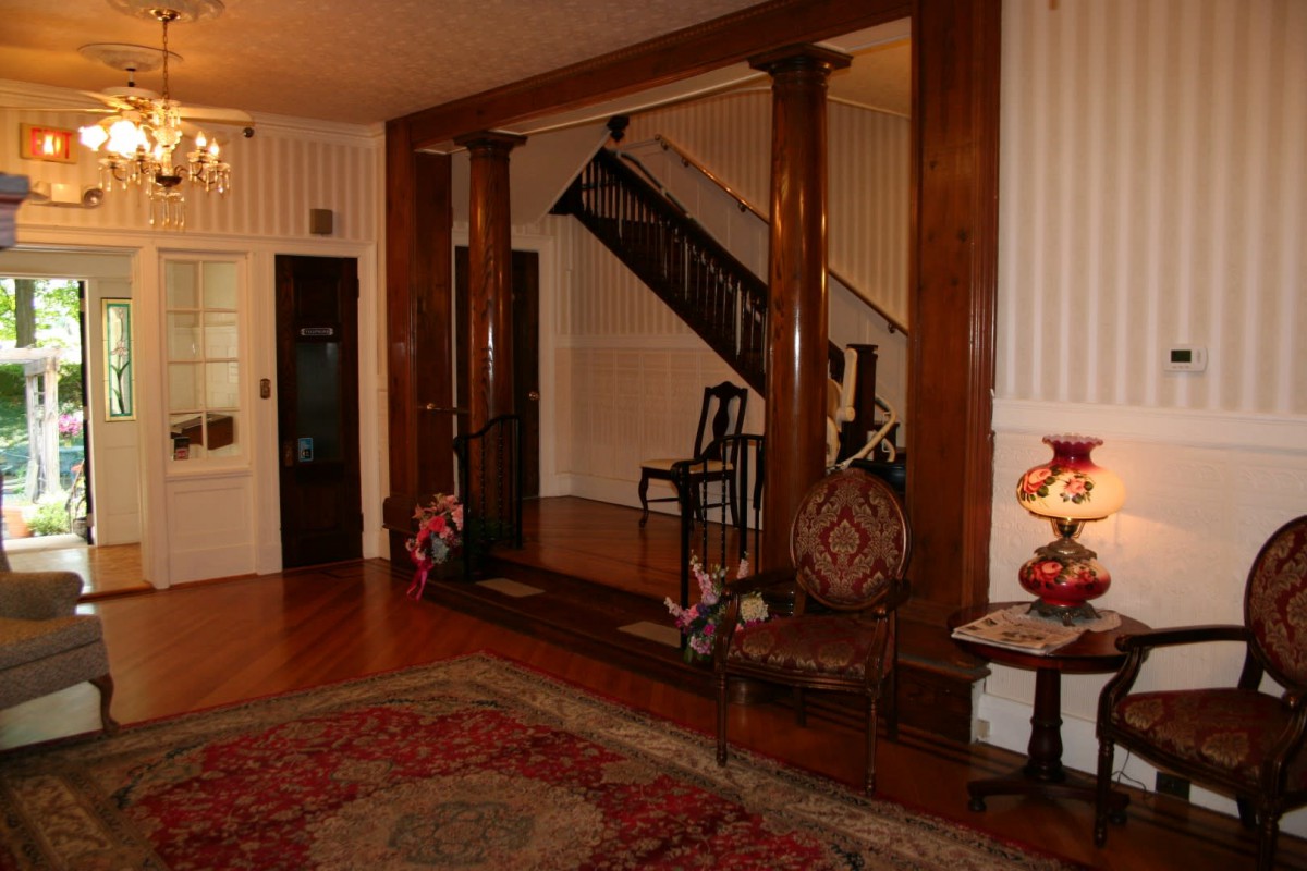 A vintage hallway with antique furniture and a wooden staircase.