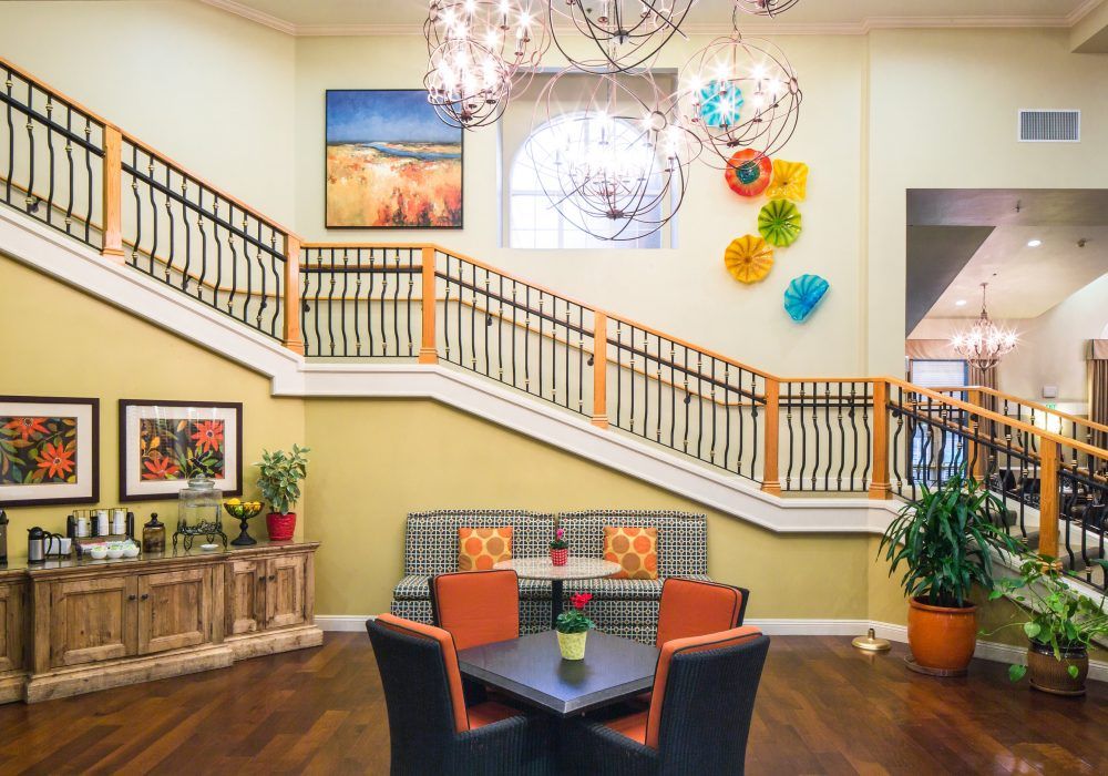 A modern lobby featuring colorful artwork, unique lighting fixtures, and comfortable seating beside a staircase.
