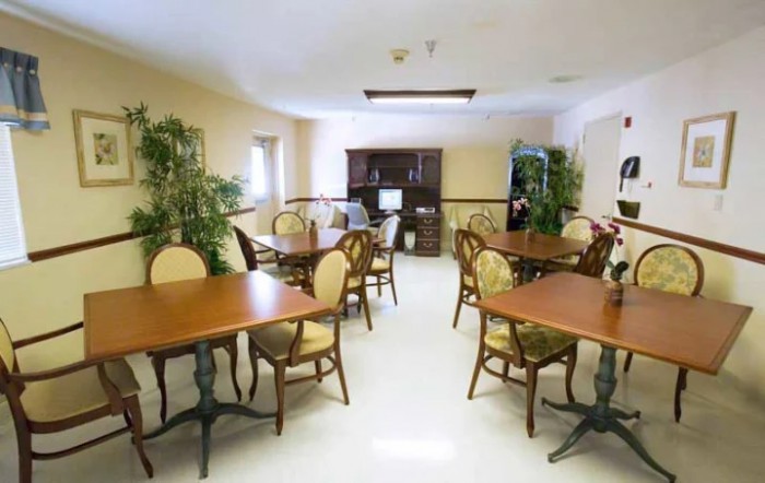 A well-lit dining area with wooden tables and chairs, complemented by indoor plants.