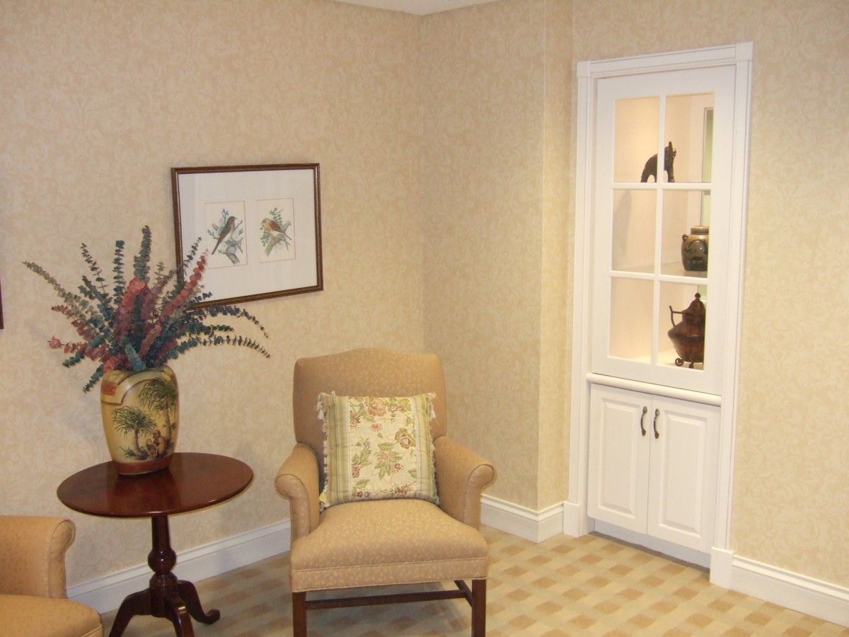 A cozy corner with a beige armchair, side table, and decorative shelving.