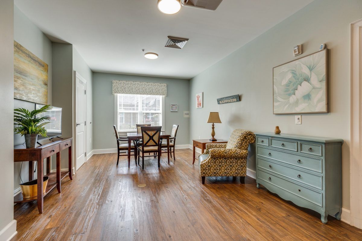A cozy living room with a dining table and chairs, featuring hardwood floors and comfortable seating.