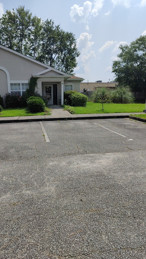 A view of a building front with an empty parking lot and well-maintained green grass.