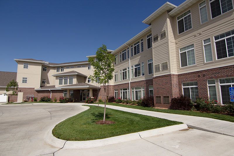 A modern three-story apartment complex with well-maintained landscaping and a circular driveway.