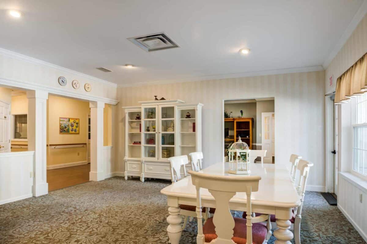 A cozy dining room with a white table and chairs, surrounded by elegant furnishings and warm lighting.