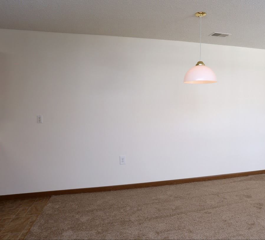 An empty room with white walls and a ceiling light fixture.
