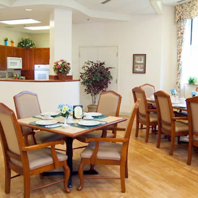 A cozy dining area with neatly arranged tables and chairs, surrounded by decorative plants.