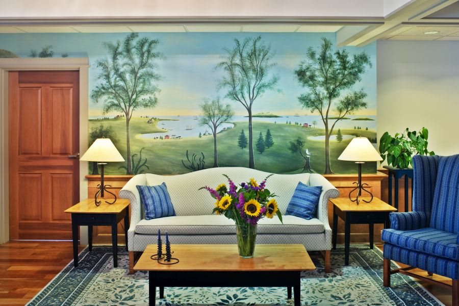 A cozy living room with a scenic mural and elegant furnishings.