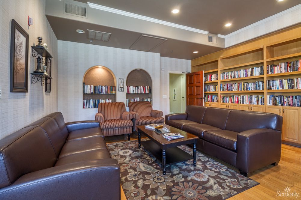 A cozy library room with leather couches, bookshelves, and a patterned carpet.