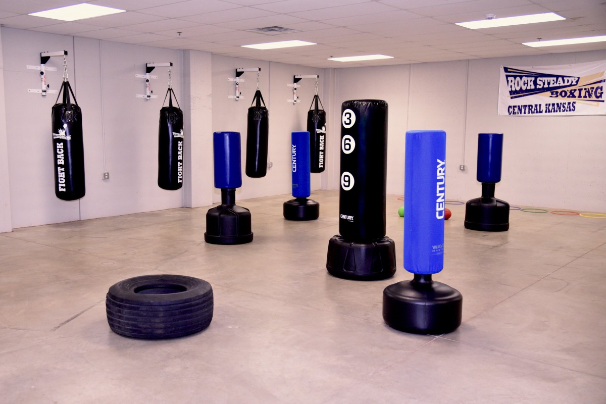 A gym room equipped with multiple punching bags and a tire for fitness training.