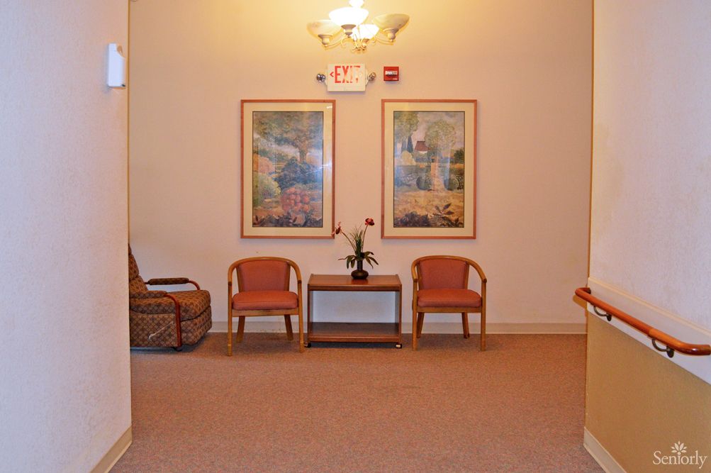 A cozy waiting area with two chairs, a small table, and decorative artwork on the wall.