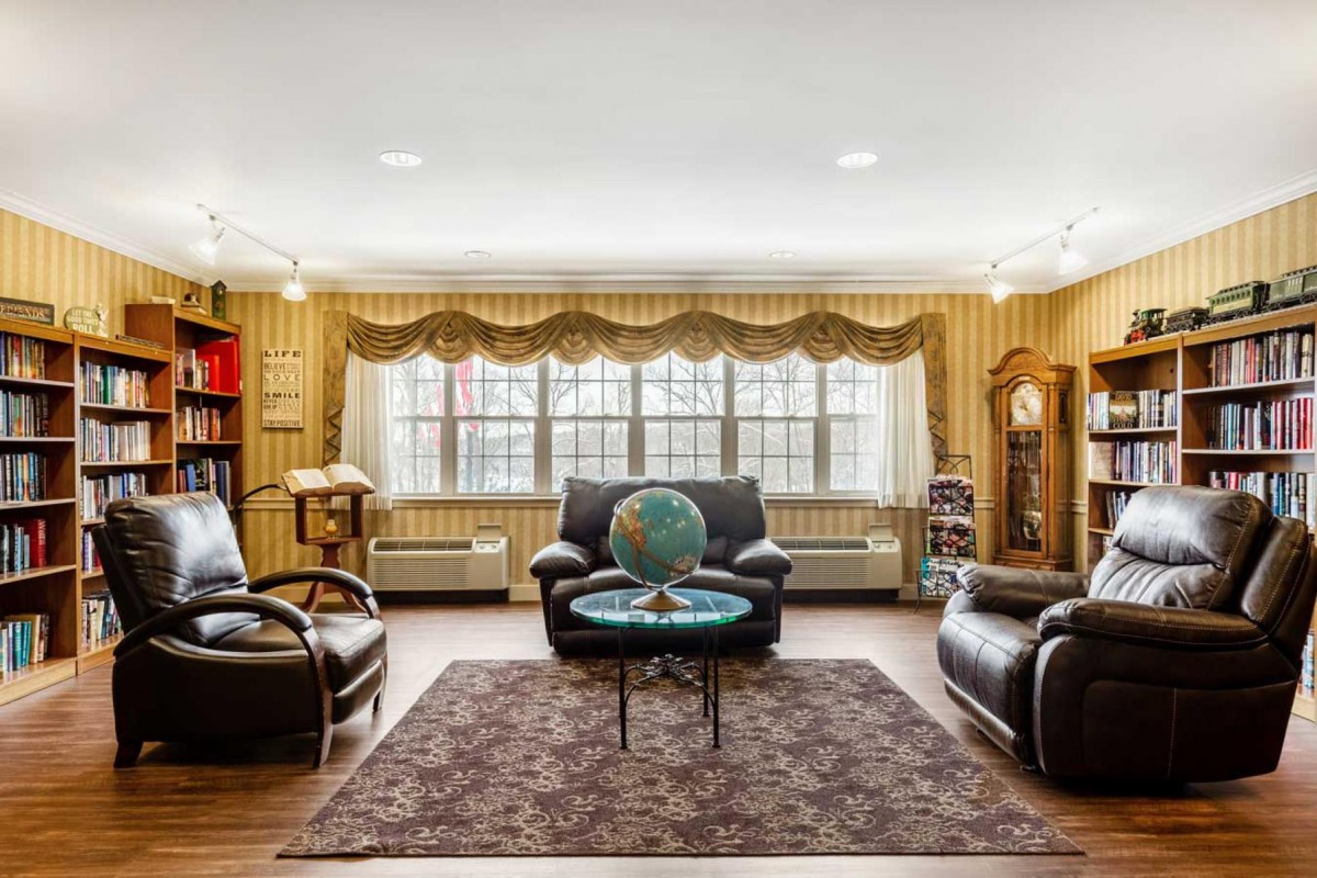 A cozy living room with leather furniture and a central globe under a large window.