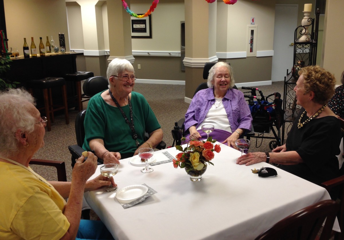 A group of seniors enjoying a conversation around a dining table.