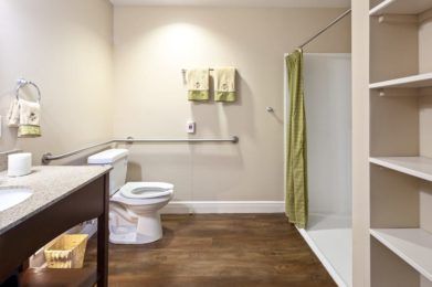 A clean and accessible bathroom with a shower, toilet, and grab bar.