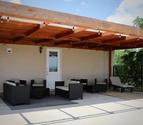 A relaxing outdoor patio with a wooden pergola and comfortable seating.