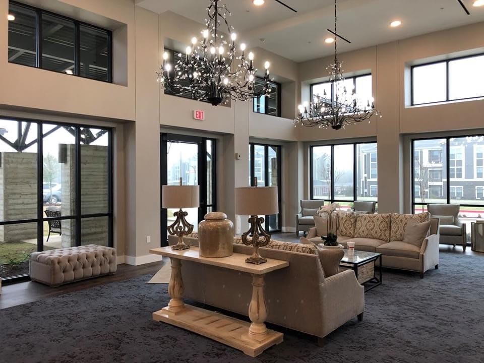 A luxurious living room with chandeliers and large windows.