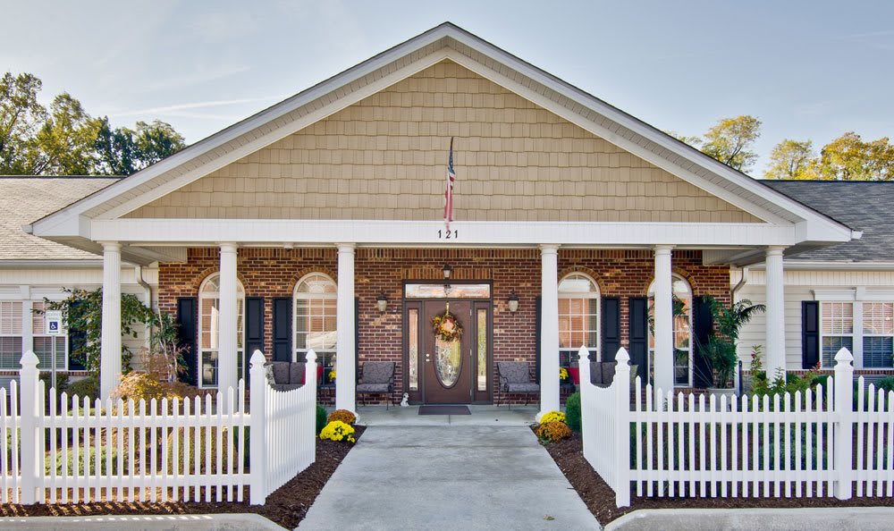 A charming house entrance with a brick faade, white columns, and a decorative front door.