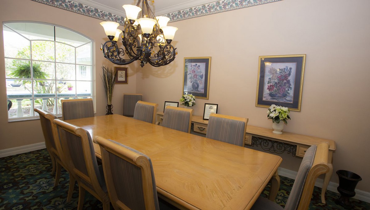 A well-appointed dining room featuring a large wooden table, elegant chandelier, and framed artwork.