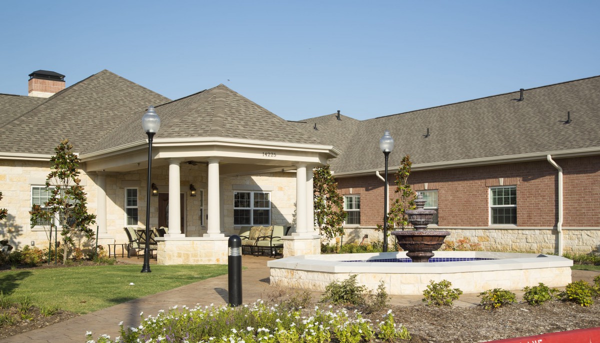 A suburban-style building with a garden and fountain in the foreground.