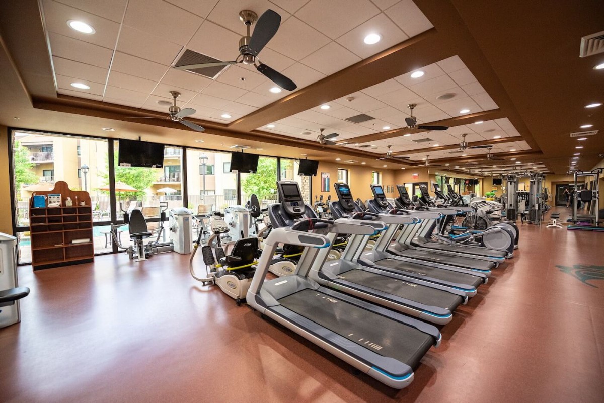 A spacious gym with a row of treadmills and other exercise equipment.