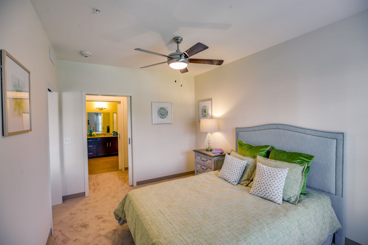 A cozy bedroom with a comfortable bed, stylish bedding, and a ceiling fan.