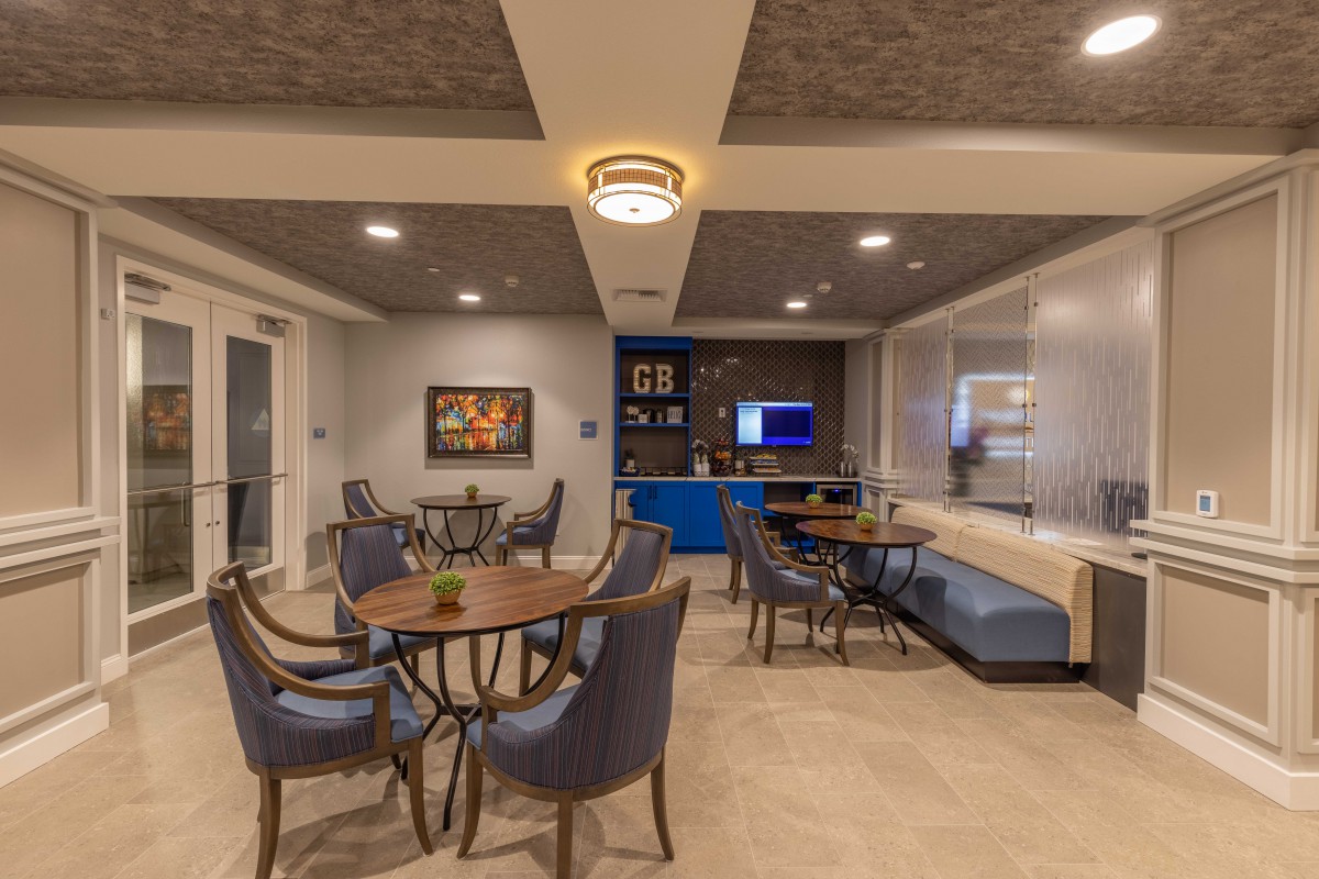 A modern lounge area featuring tables, chairs, and elegant lighting.