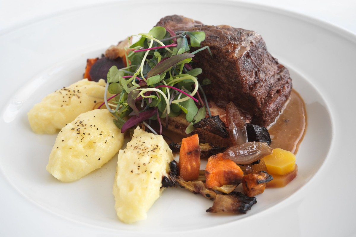 A gourmet beef dish served with mashed potatoes and roasted vegetables.