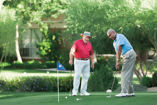 Two men enjoying a round of golf, practicing their putting skills on a sunny day.