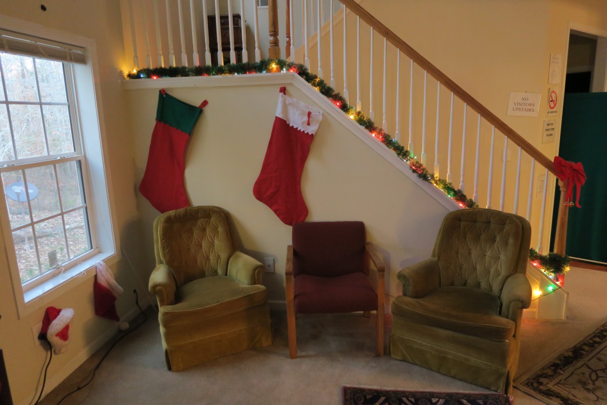 A cozy living room decorated for Christmas with stockings and festive lights.