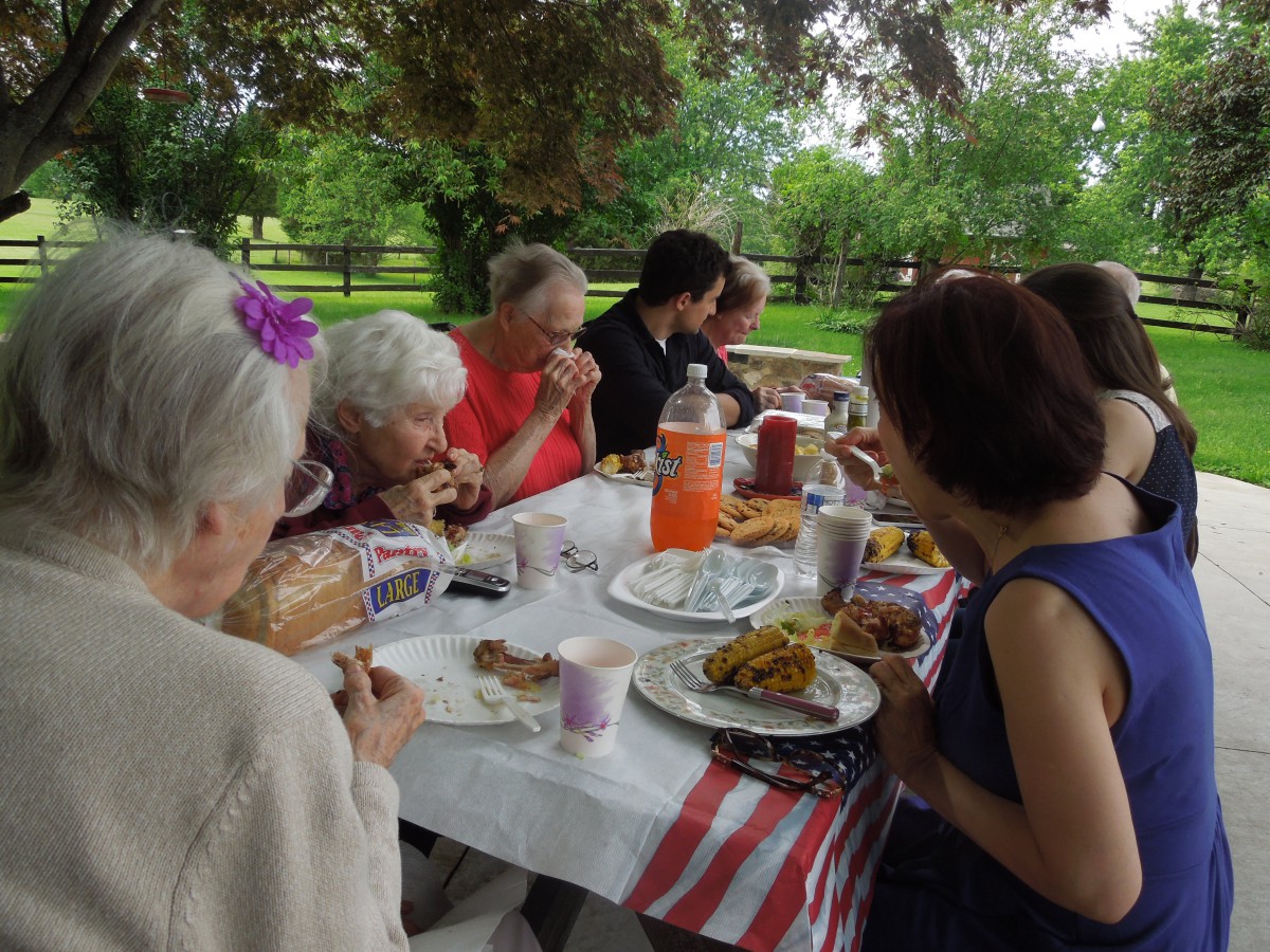 A family enjoying a meal together at an outdoor picnic table.