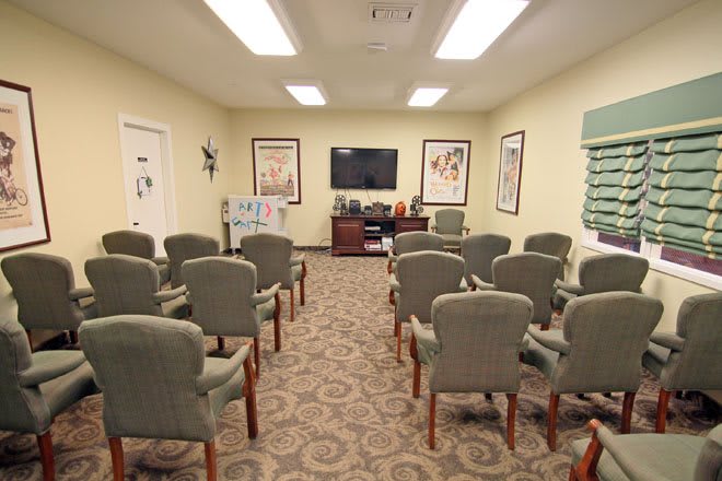 A conference room arranged with chairs facing a television, ready for a presentation.