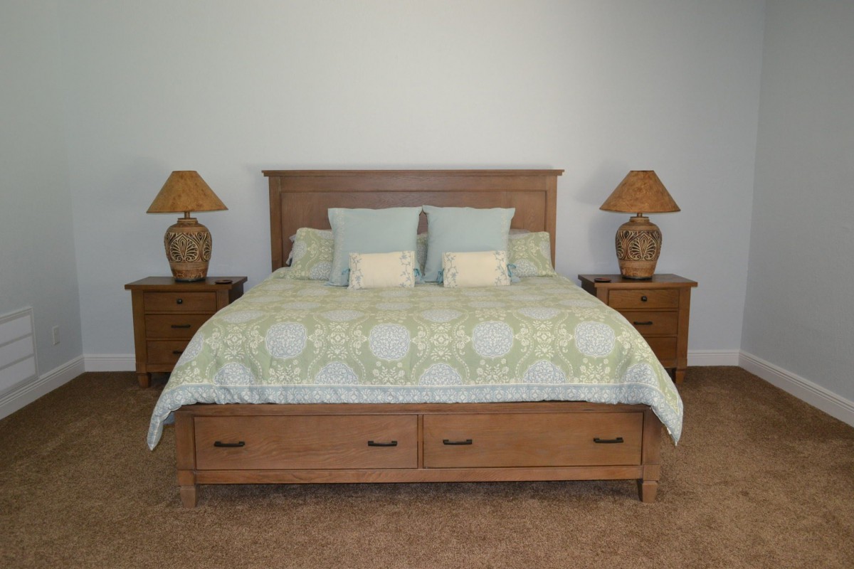 A cozy bedroom setup featuring a wooden bed with matching nightstands and decorative lamps.