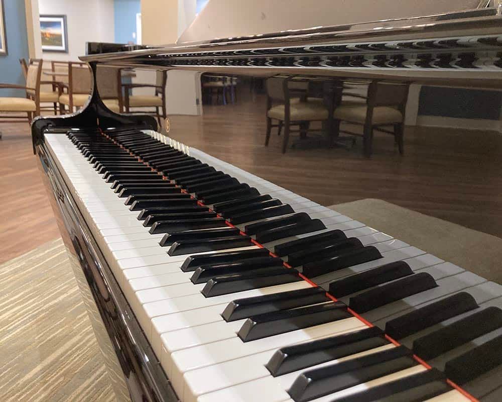 A close-up view of a piano keyboard with reflections on its surface.