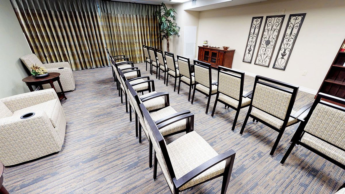 An empty meeting room with neatly arranged chairs facing a small cabinet.