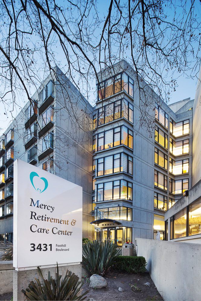 Exterior view of Mercy Retirement & Care Center with illuminated windows and a prominent sign.