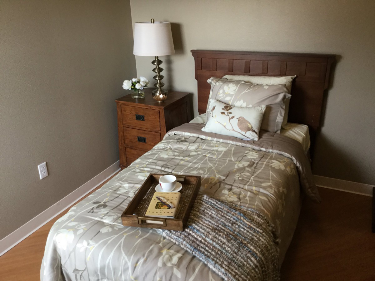 A cozy bedroom with a single bed, nightstand, and decorative tray.