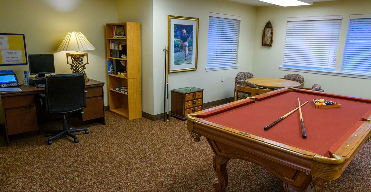 A cozy game room featuring a red pool table, bookshelf, and decorative elements.