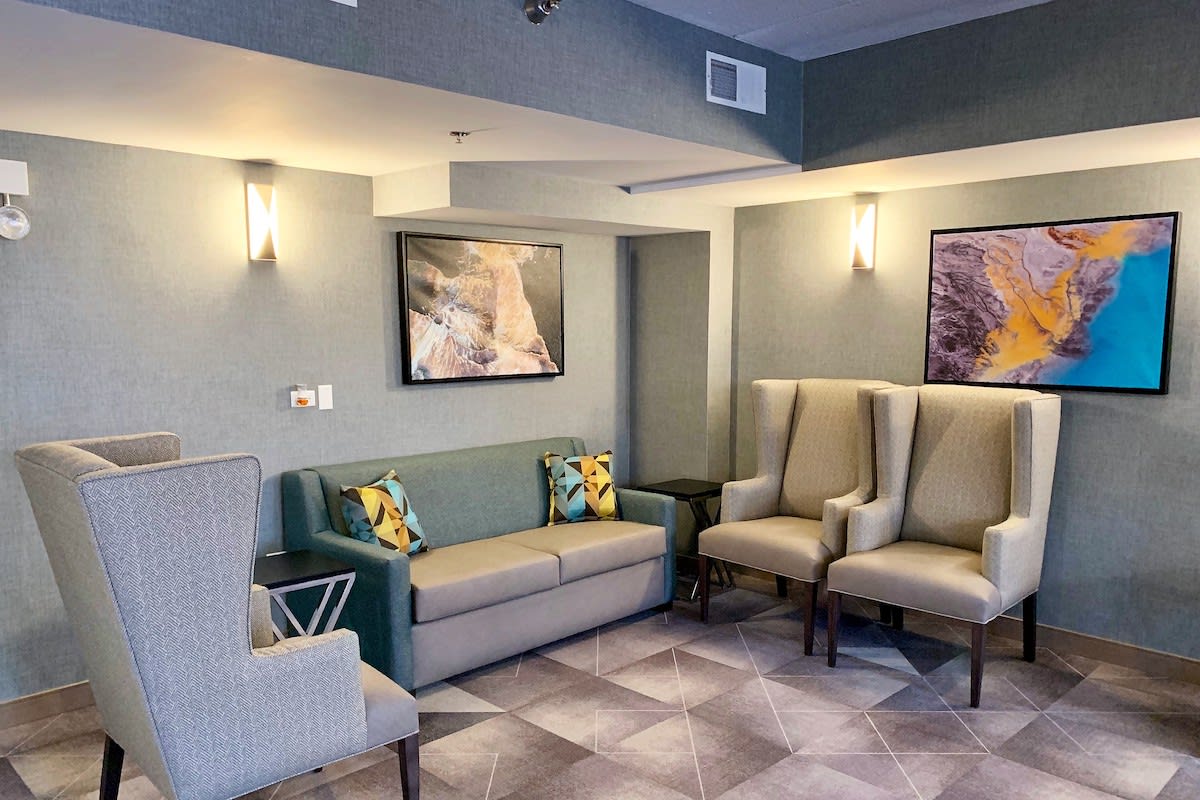 A modern lobby seating area featuring stylish chairs and a sofa, complemented by contemporary artwork on the walls.