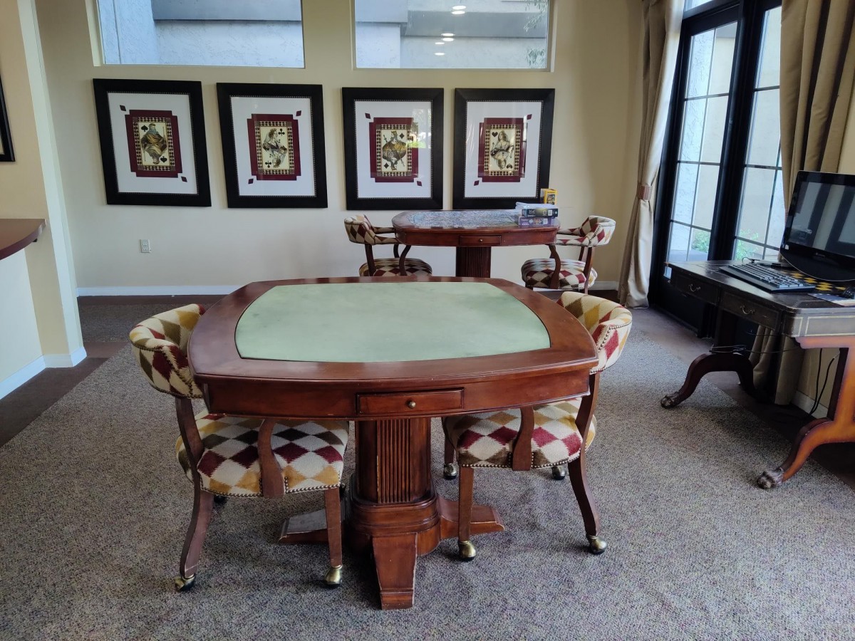 A room with a poker table and chairs, featuring decorative wall art.