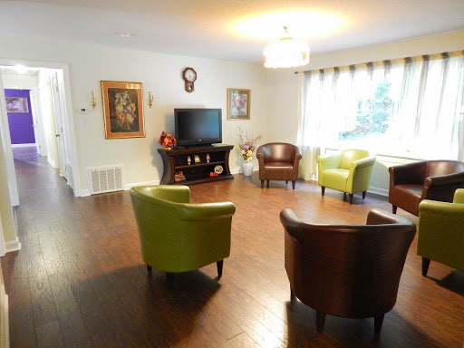 A cozy living room featuring colorful chairs, a television, and decorative artwork.