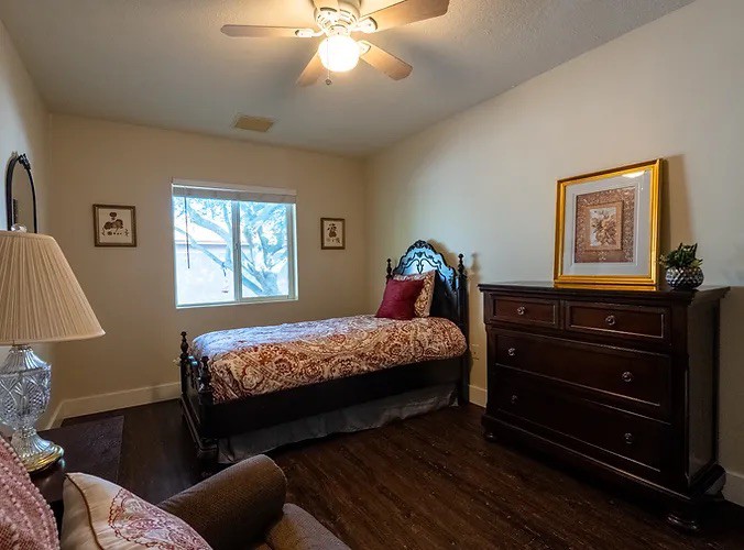 Cozy bedroom with two beds, a dresser, and wall art, illuminated by natural light from the window.