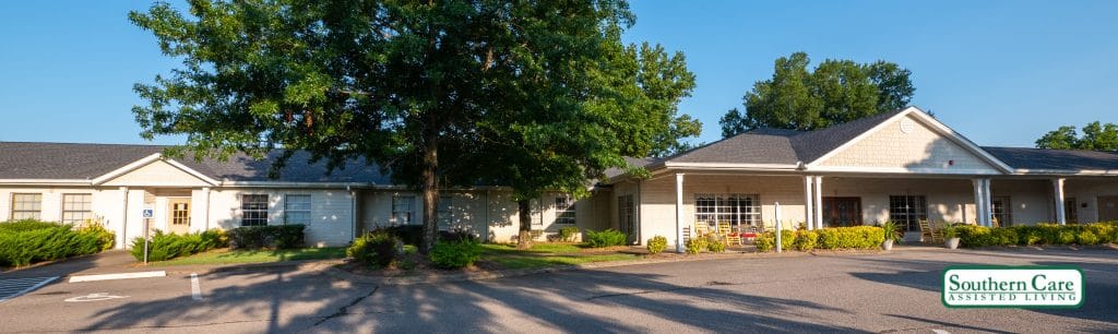 A suburban house surrounded by trees, basking in sunlight with a spacious driveway.