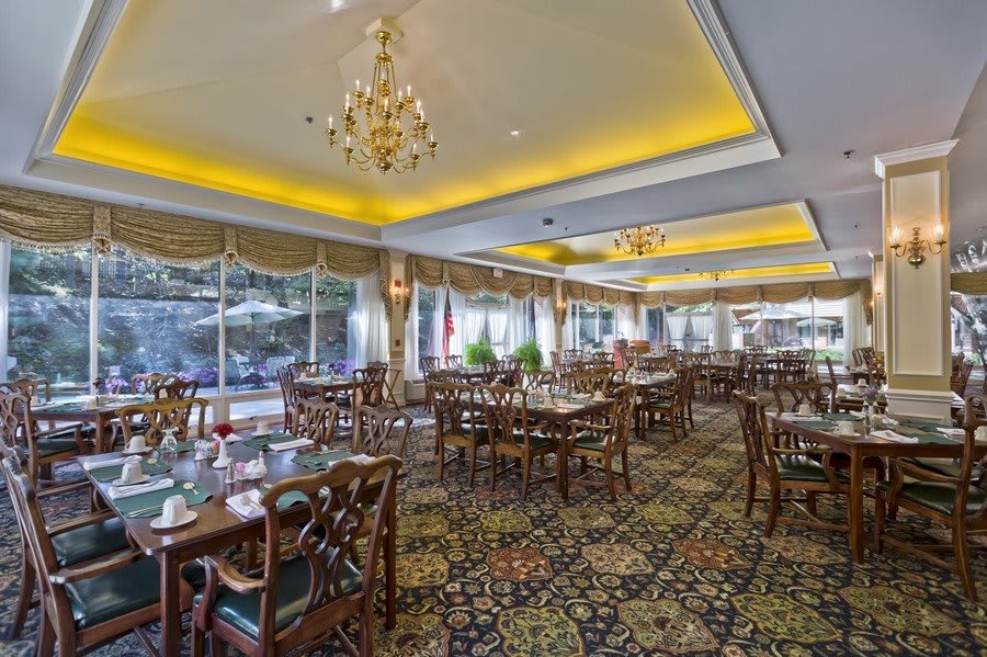 An elegant restaurant dining room with chandeliers and neatly arranged tables and chairs.