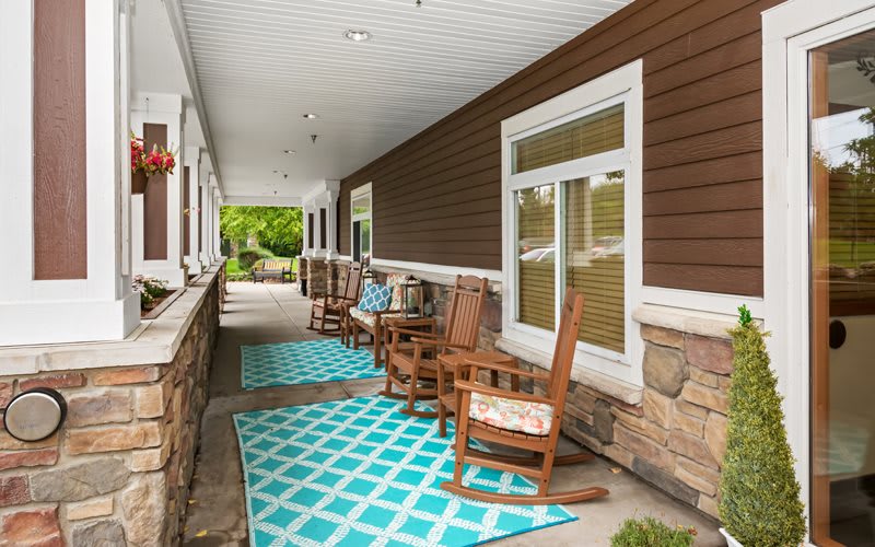 A cozy covered porch with rocking chairs and patterned rugs.