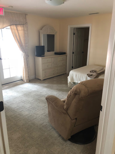 A cozy and simple bedroom setup with a dresser, television, and comfortable seating.